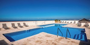A rooftop pool with clear blue water, surrounded by lounge chairs and a view of the ocean. - Ocean View 2Br Condo-balcony-beach-pool - 802 (Puerto Vallarta)