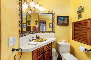 A bathroom with a mirror, sink, toilet, and a wall-mounted cross. - Ocean View 2Br Condo-balcony-beach-pool - 802 (Puerto Vallarta)