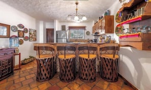 A kitchen with a central island, bar stools, a refrigerator, and decorative plates on the wall. - Ocean View 2Br Condo-balcony-beach-pool - 802 (Puerto Vallarta)