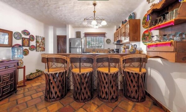 Une cuisine dotée d’un îlot central, de tabourets de bar, d’un réfrigérateur et d’assiettes décoratives accrochées au mur.