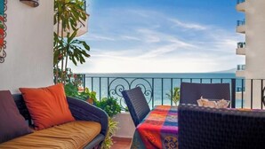 Un balcon avec un canapé, une table et une vue sur la mer.
