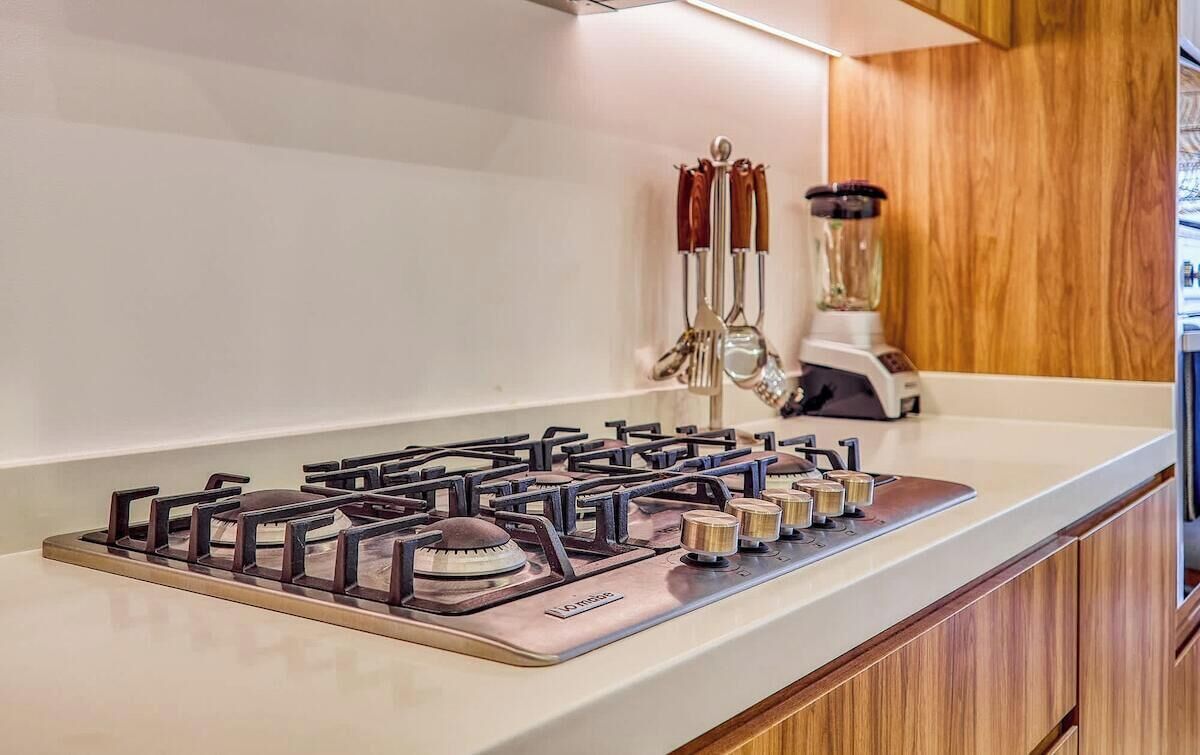 A kitchen with a gas stove, wooden cabinets, and a blender on the counter.