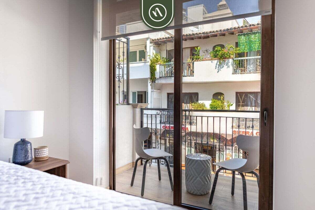 Un balcon avec deux chaises, une petite table et une plante en pot.
