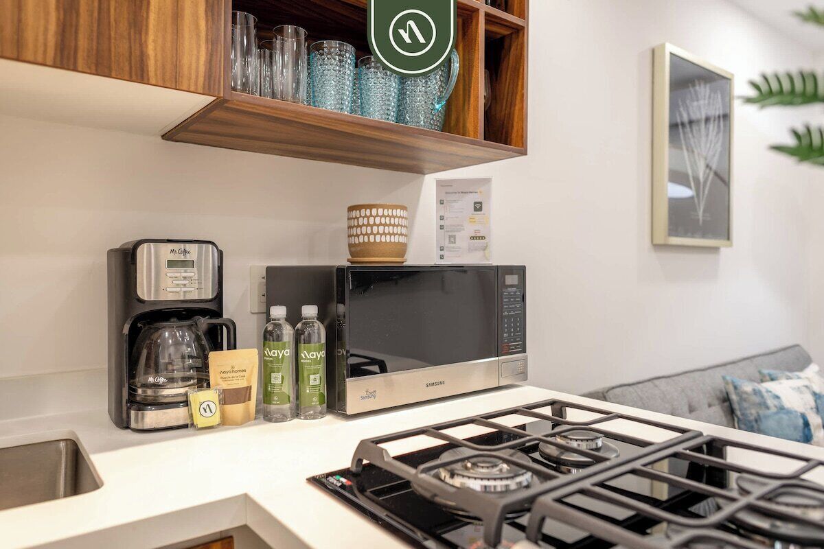 Una cocina equipada con microondas, cafetera y estufa a gas.