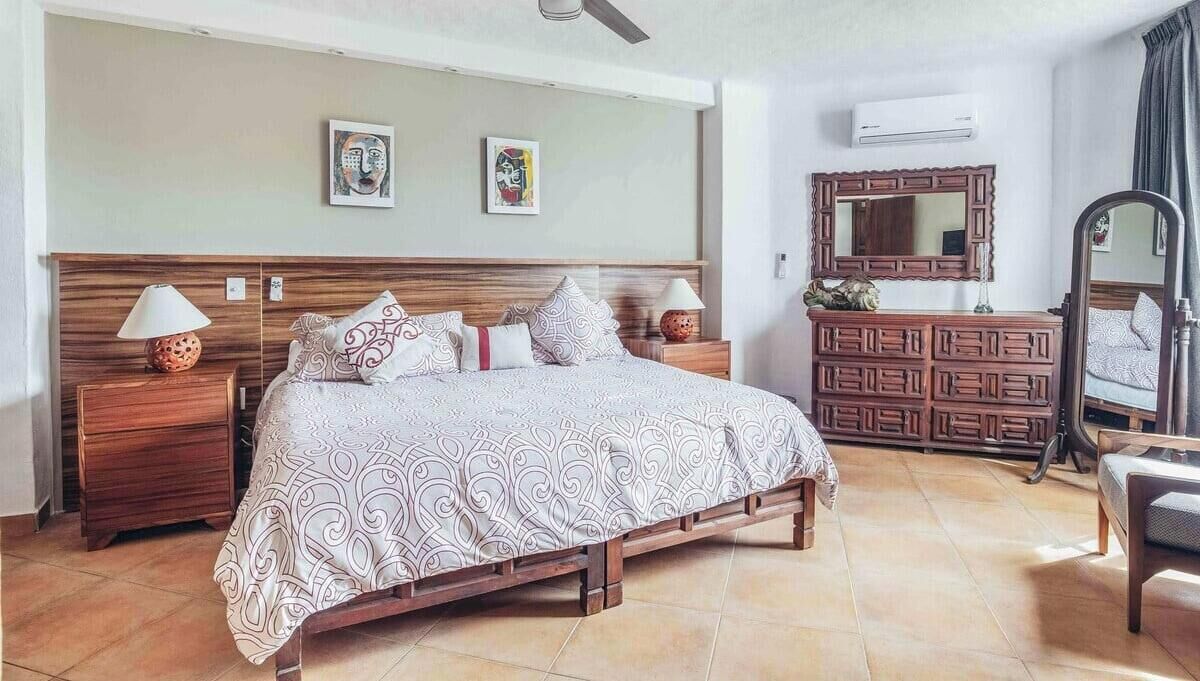 Ein Schlafzimmer mit einem hölzernen Bett, zwei Nachttischen, einer Kommode, einem Spiegel und Bildern an der Wand.
