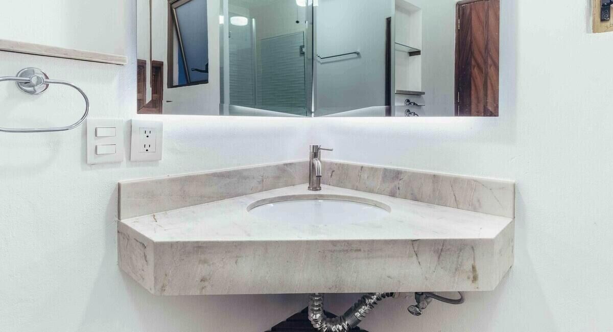 A bathroom with a marble sink, a mirror, and a towel rack.