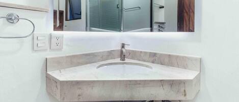 A bathroom with a marble sink, a mirror, and a towel rack.