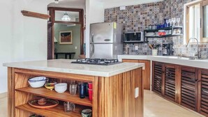 A kitchen with a central island, a refrigerator, a microwave, and a tiled backsplash.