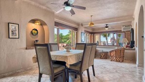 Un comedor con una mesa, sillas, ventiladores de techo y vistas al exterior.