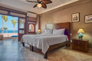 A bedroom with a bed, nightstand, and a view of the beach.