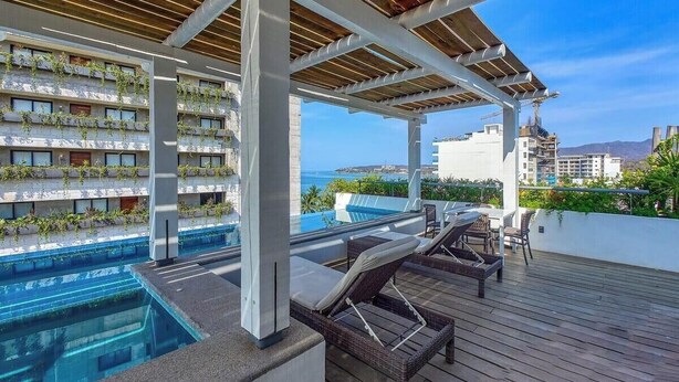A rooftop pool area with lounge chairs and a view of the sea. - New 1 BR Condo - Oceanview Pool - 2 min to Beach (Bucerías)