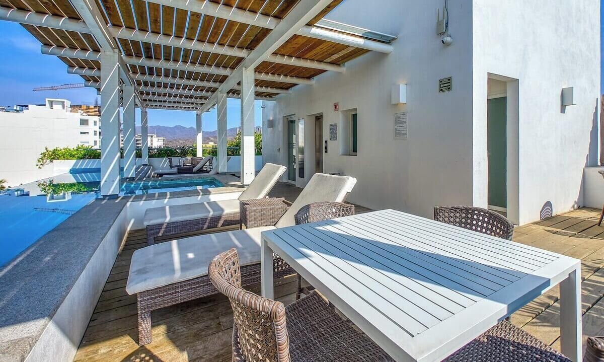 Een dakterras met een zwembad, ligbedden, een tafel en een pergola.