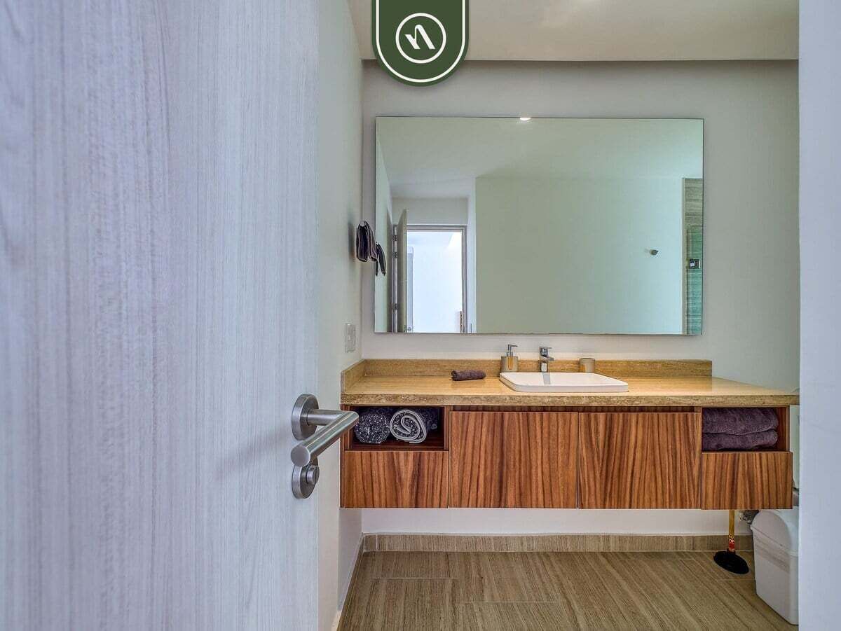 Une salle de bain avec un meuble-lavabo en bois, un miroir et un porte-serviettes.
