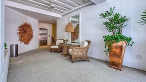 A modern interior with wicker furniture, a large mirror, and a potted plant. - New 1 BR Condo - Oceanview Pool - 2 min to Beach (Bucerías)