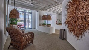A modern interior with wicker furniture, pendant lights, and a large decorative wall piece. - New 1 BR Condo - Oceanview Pool - 2 min to Beach (Bucerías)