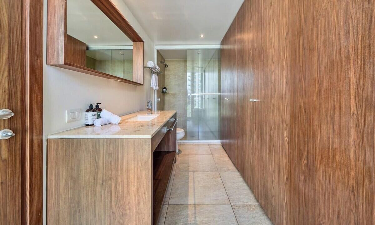 Une salle de bain moderne avec un meuble-lavabo en bois, un grand miroir et une cabine de douche en verre.