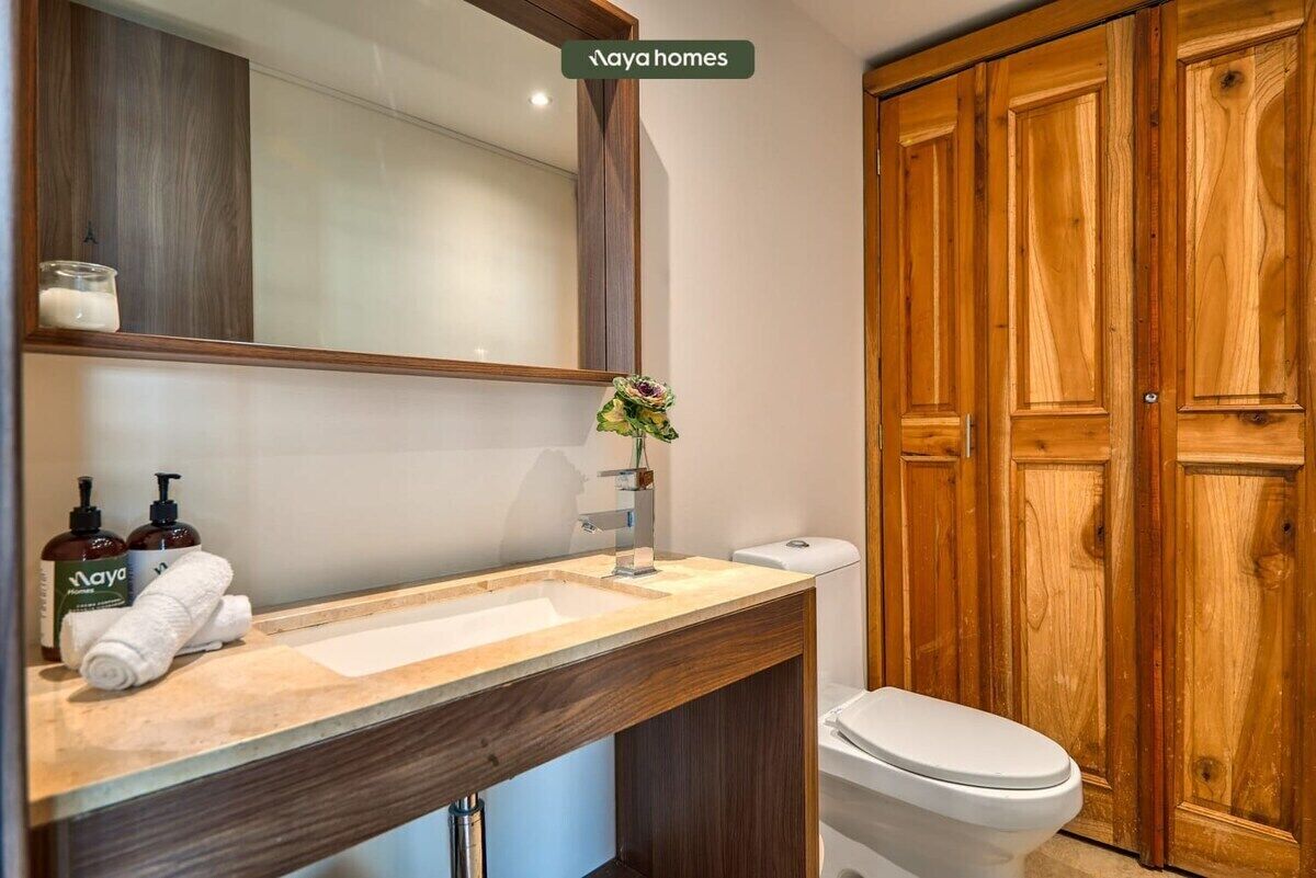 A bathroom with a wooden vanity, a white toilet, and a mirror.