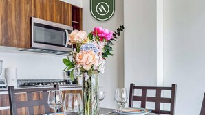 A dining table set with plates, glasses, and a vase of flowers.