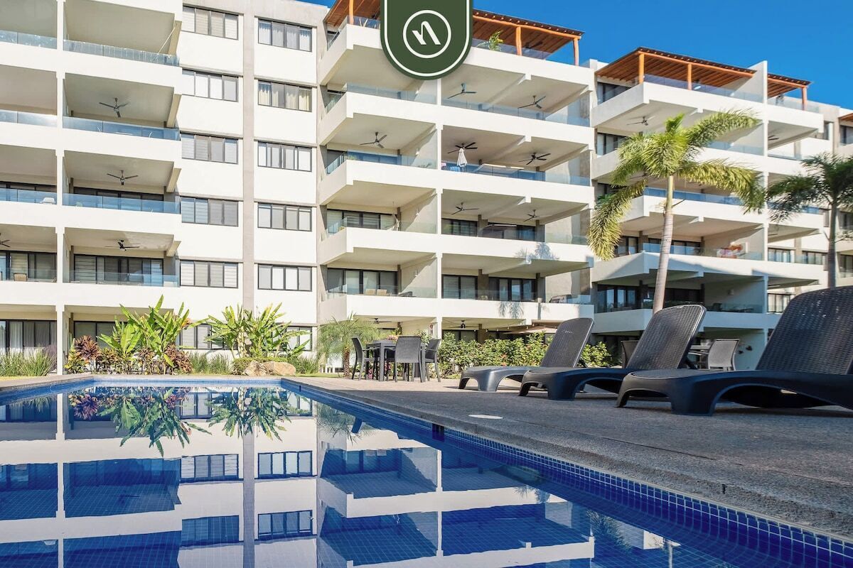 A multi-story hotel with balconies, a swimming pool, and outdoor seating.