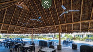 An outdoor pool area with lounge chairs, tables, and ceiling fans.