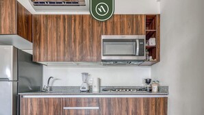 A kitchen with wooden cabinets, a microwave, a sink, a blender, and a stove.