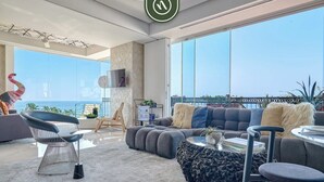 Ein modernes Wohnzimmer mit großem Fenster, einer Couch, einem Sessel und einem Couchtisch.