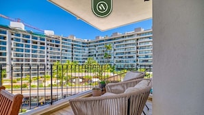 A balcony with wicker furniture, a view of high-rise buildings, and a construction crane in the background. - 3BR Condo With Private Balcony - Pool - Marina` (Puerto Vallarta)