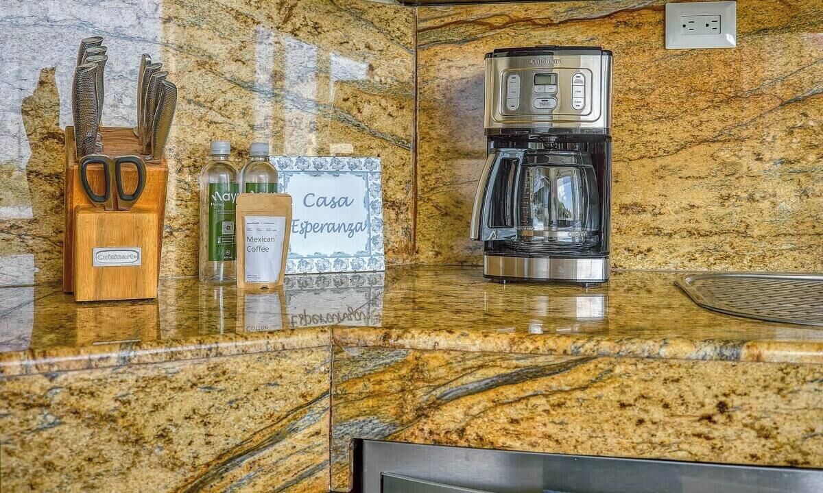 Una encimera de cocina con una cafetera, un juego de cuchillos y un letrero que dice 'Casa Esperanza'.