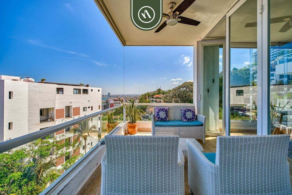 A balcony with wicker furniture, a ceiling fan, and a view of the cityscape.