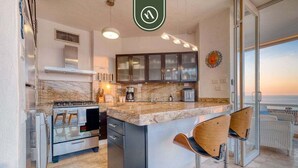 Una cucina moderna con un piano di lavoro in marmo, elettrodomestici in acciaio inox e una grande isola con sgabelli da bar.