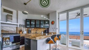 Una cucina moderna con un piano di lavoro in marmo, un piano cottura integrato e una grande isola con sgabelli da bar.