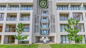 Un hotel moderno de varios pisos con un atrio central, amplias ventanas y una escalera que conduce a la entrada.