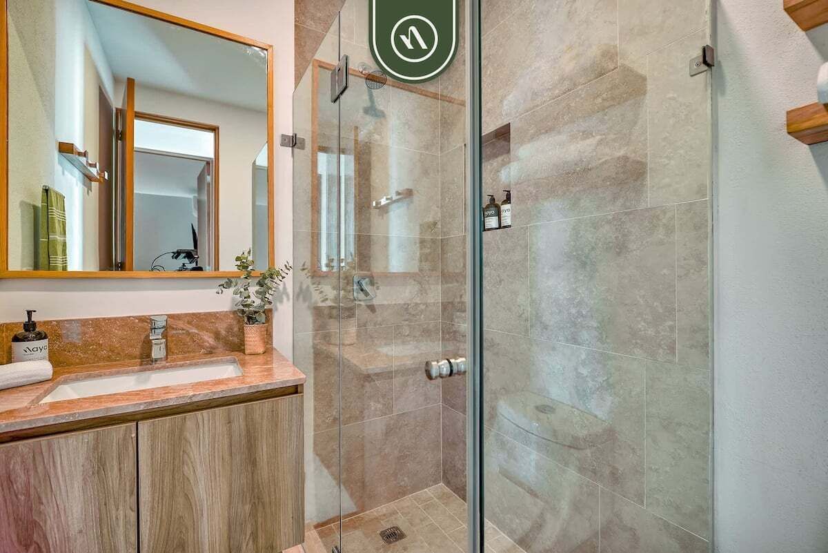 A modern bathroom with a glass-enclosed shower, a wooden vanity, and a large mirror.