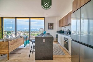 A modern kitchen with a large island, stainless steel appliances, and a view of the city.
