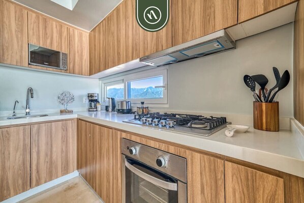 A modern kitchen with wooden cabinets, a built-in oven, a gas stove, and a coffee maker.