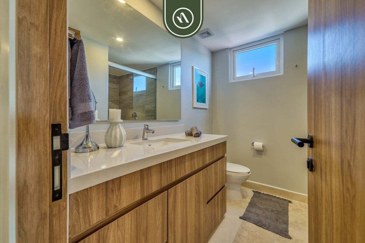 Un baño moderno con tocador de madera, un espejo grande y un inodoro.