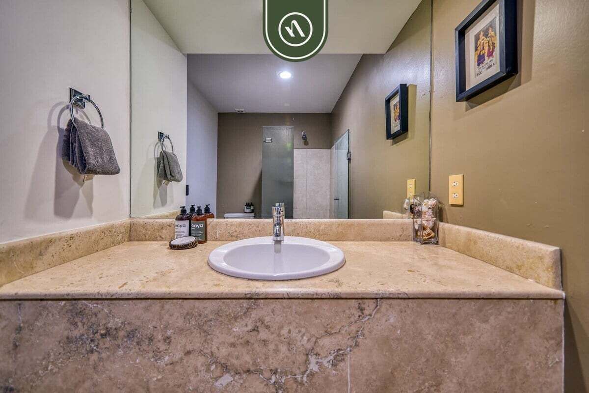 A bathroom with a sink, mirror, towel rack, and framed pictures on the wall.