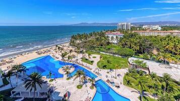 Ein Resort mit großem Pool, Palmen und einem Strand.