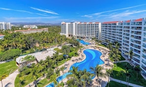 A resort with a large pool, palm trees, and high-rise buildings.