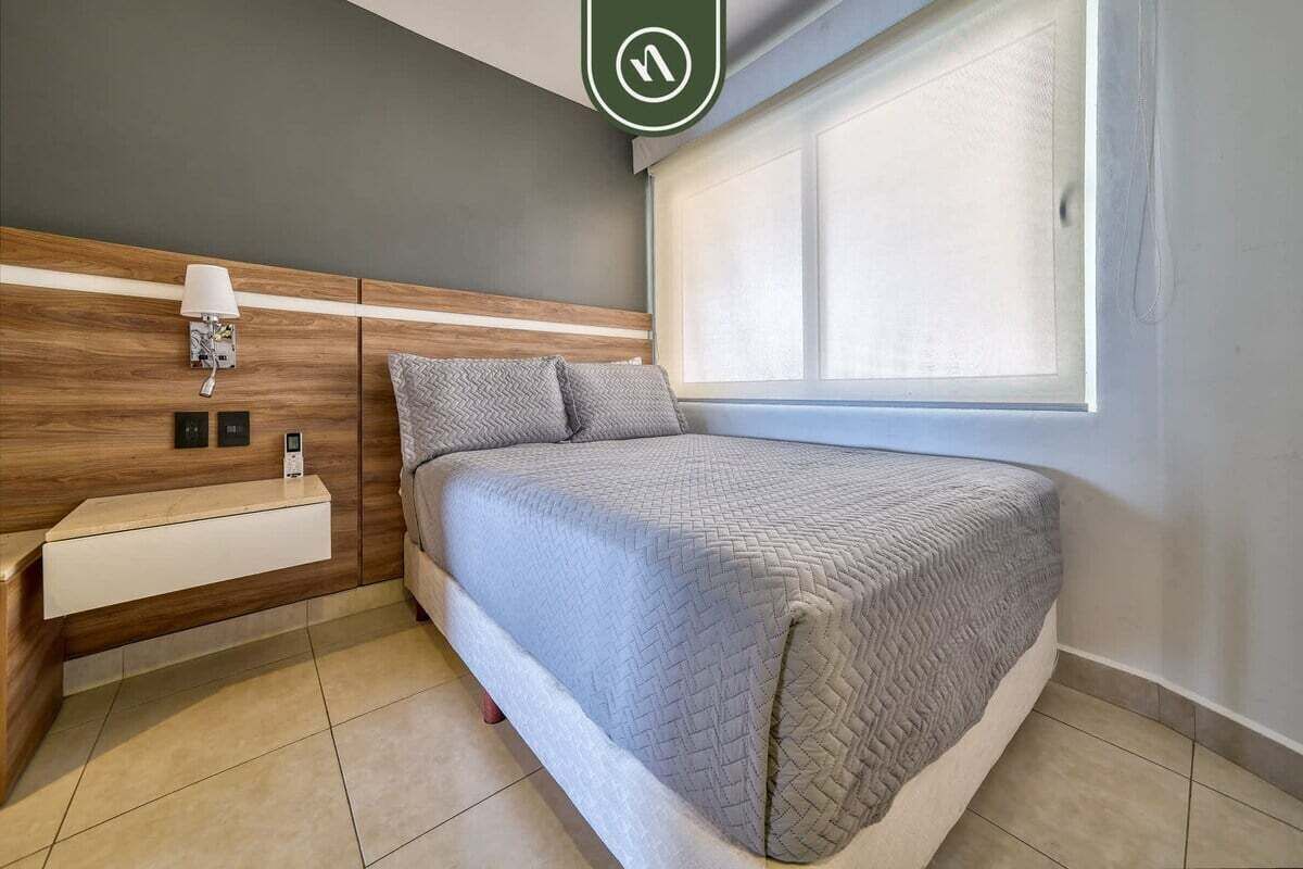 Une chambre à coucher moderne avec un lit, une table de chevet, une lampe et une fenêtre.
