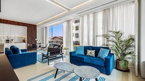 Una sala de estar moderna con un sofá azul, una mesa de centro y un comedor con mesa y sillas.