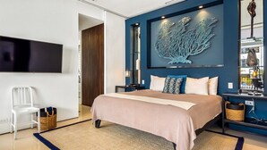 Un dormitorio moderno con cama, televisión, un elemento decorativo en la pared y una mesita de noche.