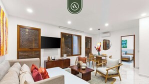 A modern hotel room with a sofa, a dining area, a bed, and a TV. - New 1 BR Condo - Rooftop Pool - Romantic Zone (Puerto Vallarta)