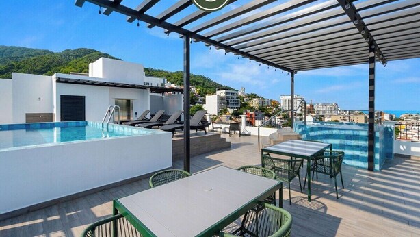 A rooftop pool area with lounge chairs, a table, and a covered seating area. - New 1 BR Condo - Rooftop Pool - Romantic Zone (Puerto Vallarta)