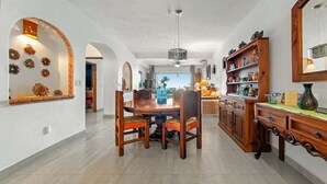 Ein großzügiger Essbereich mit Holztisch und -stühlen, einer Chandelierleuchtre und einer Küche mit Holzschränken und Regalen.