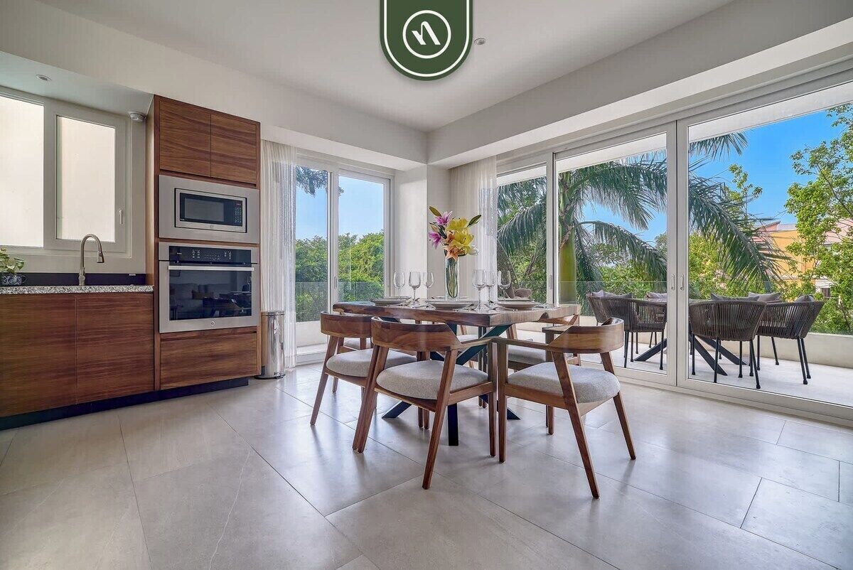 A modern kitchen with built-in appliances, a dining area with wooden chairs, and large sliding glass doors to a balcony.