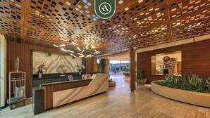A modern reception area with a wooden reception desk, a large abstract painting, and a reception cart.