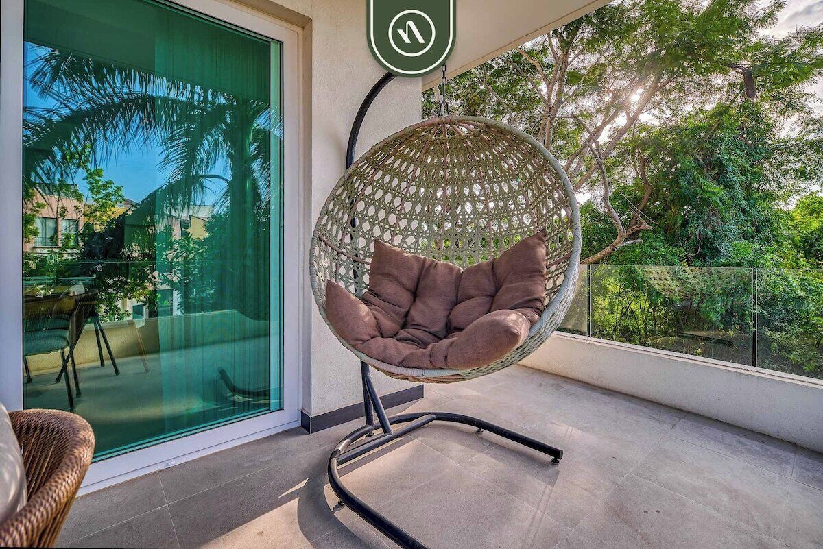 Un espace extérieur moderne aménagé avec des sièges, un fauteuil suspendu et une porte vitrée donnant sur un patio.