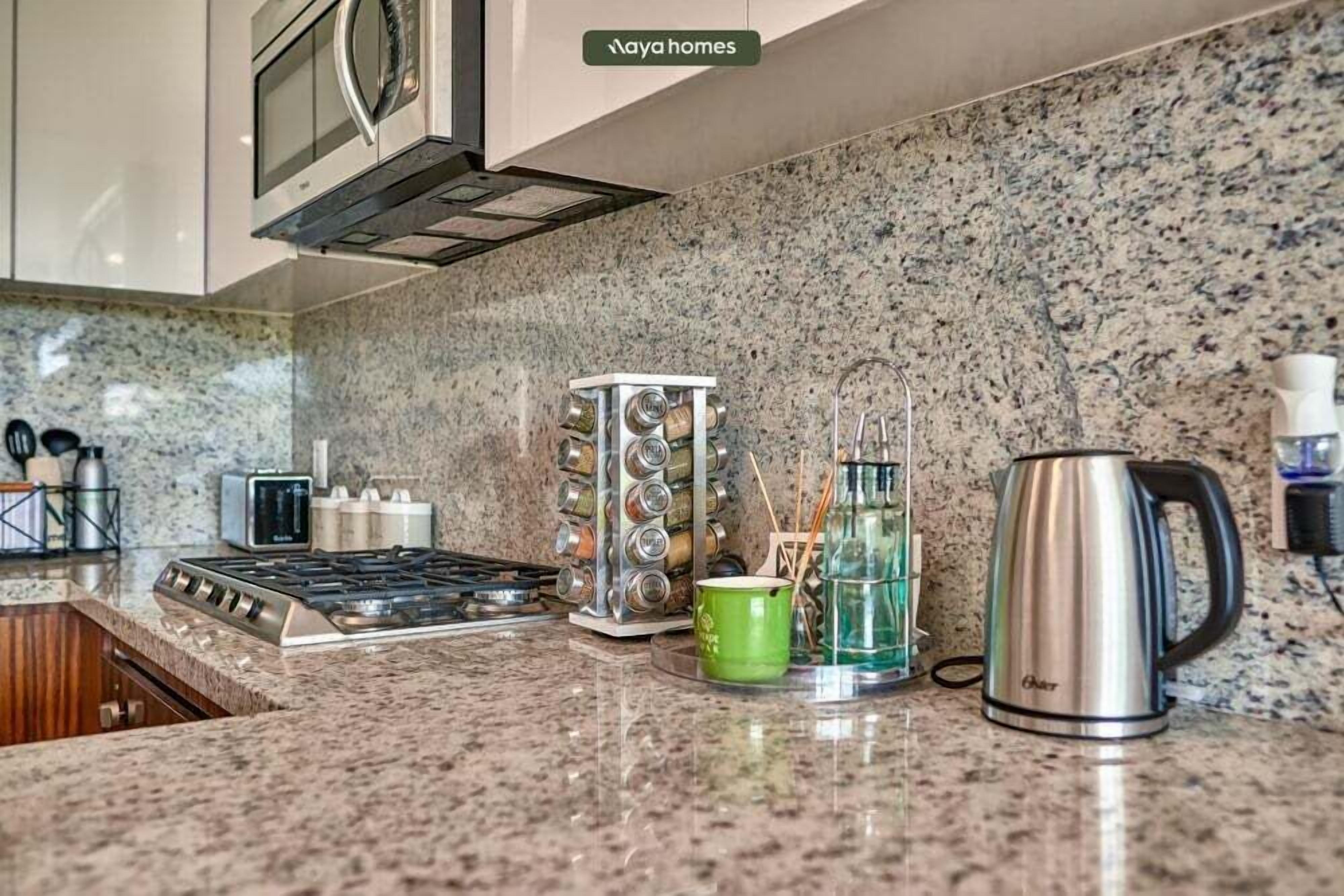 A kitchen with a gas stove, a microwave, a coffee maker, and a spice rack.