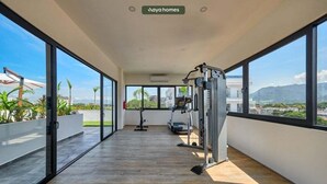 Un vaste balcon doté d’une salle de sport, de grandes fenêtres et offrant une vue sur la ville.